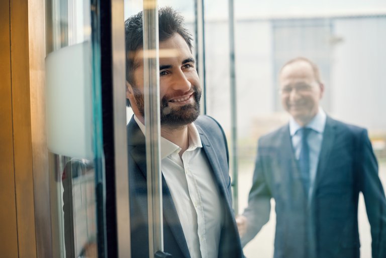 A man in a suit is looking through a window