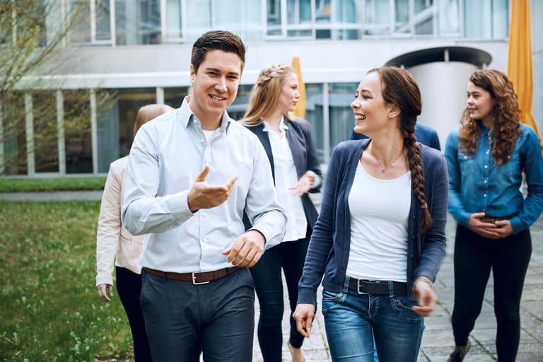 A group of young adults walk smiling through a courtyard