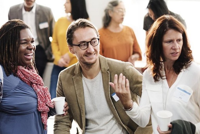 Many people from different ethnic backgrounds and of different genders having a lively conversation at a networking event 