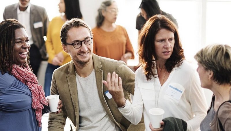 Two men and three women talking and laughing at a networking event