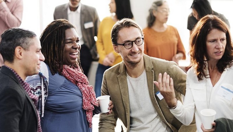Two men and three women talking and laughing at a networking event