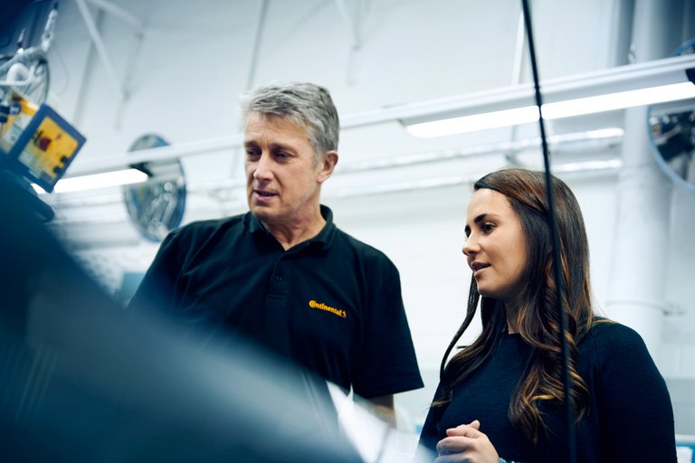Ein Mann und eine Frau in schwarzen Poloshirts schauen zusammen auf eine Sache