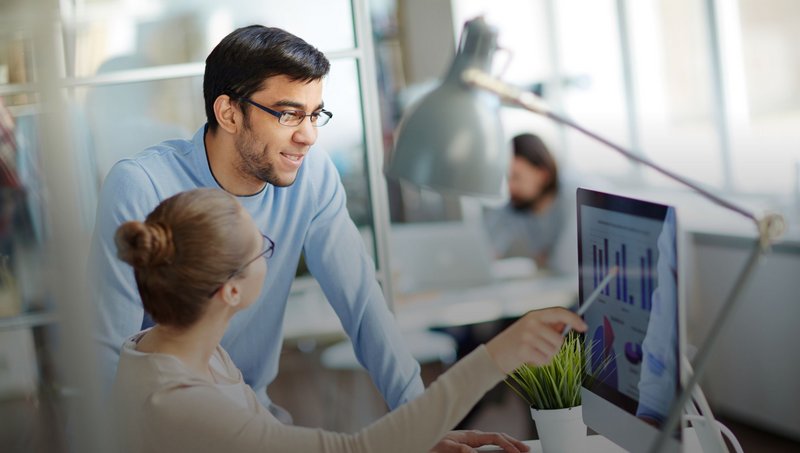 A man and a woman wearing glasses look at a PC screen