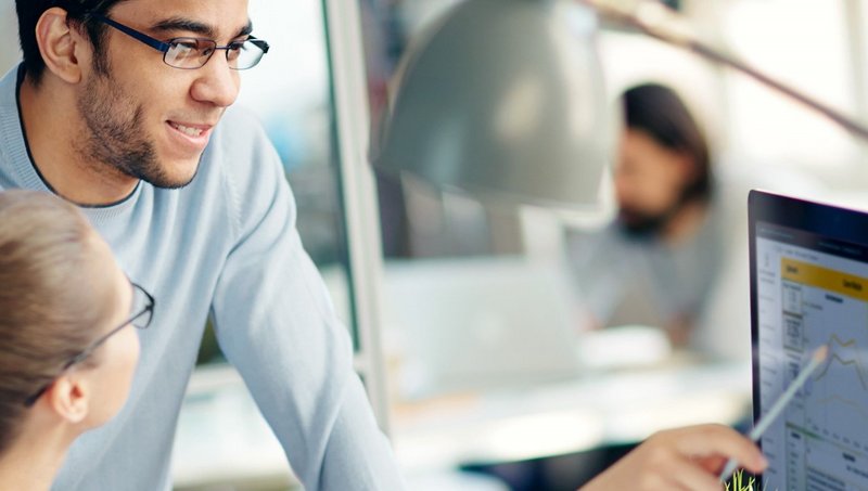 Ein Mann und eine Frau mit Brillen schauen auf einen PC-Bildschirm