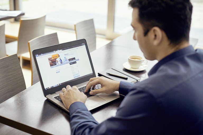 A man sits at a desk with his laptop in front of him and takes part in our online assessment