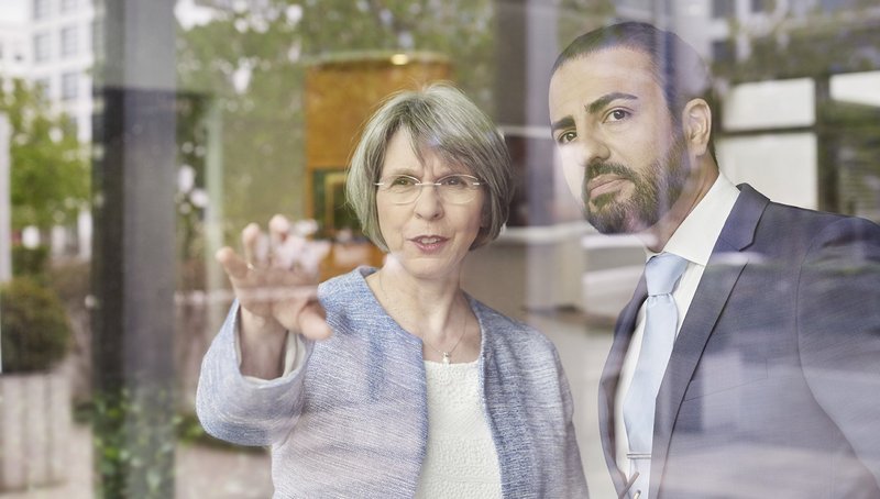 A woman is showing the man next to her something trough a window