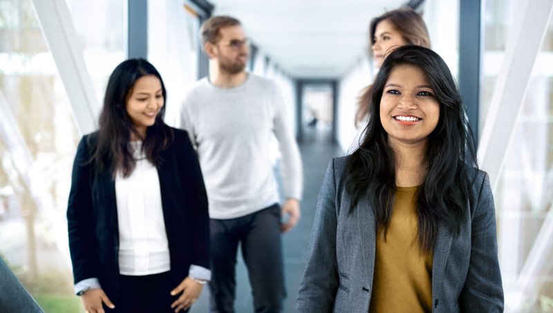 Drei junge Frauen und ein Mann gehen durch einen Korridor