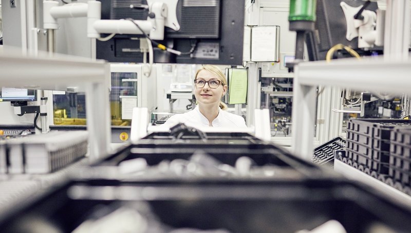 A woman is looking through a conveyer belt with boxes