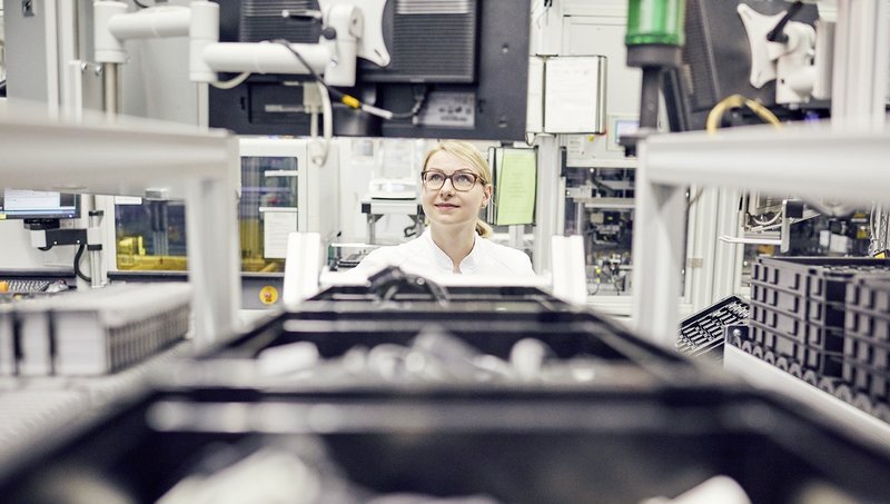 A woman is looking through a conveyer belt with boxes