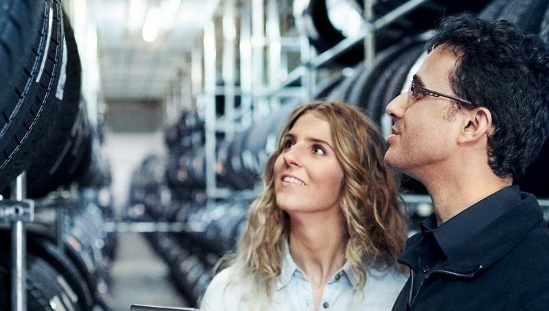 Eine junge Frau und ein Mann schauen sich ein großes Reifenregal an