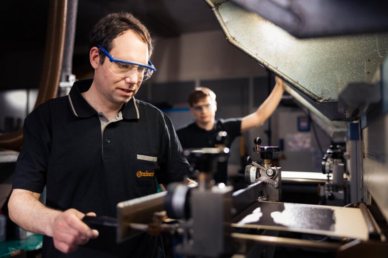 A man in a black polo shirt and safety glasses operating a technical machine