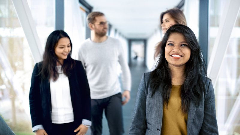 Three young women and a young man walk down a corridor
