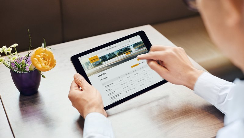 Eine Person hält ein Tablet in der Hand und sucht im Jobportal nach dem passenden Job.