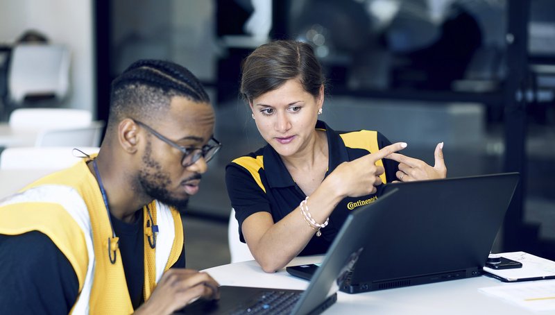 Ein Mann und eine Frau in gelben Warnwesten schauen auf einen Bildschirm