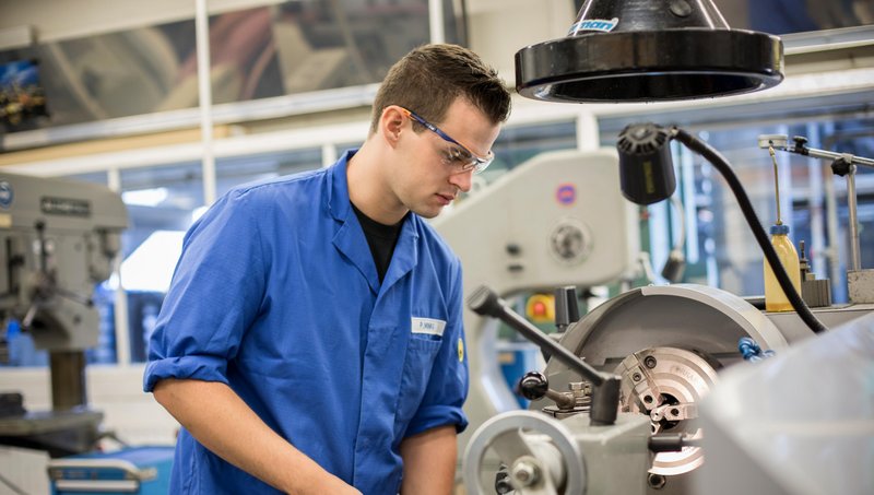 Junger Mann an einer Produktionsmaschine.