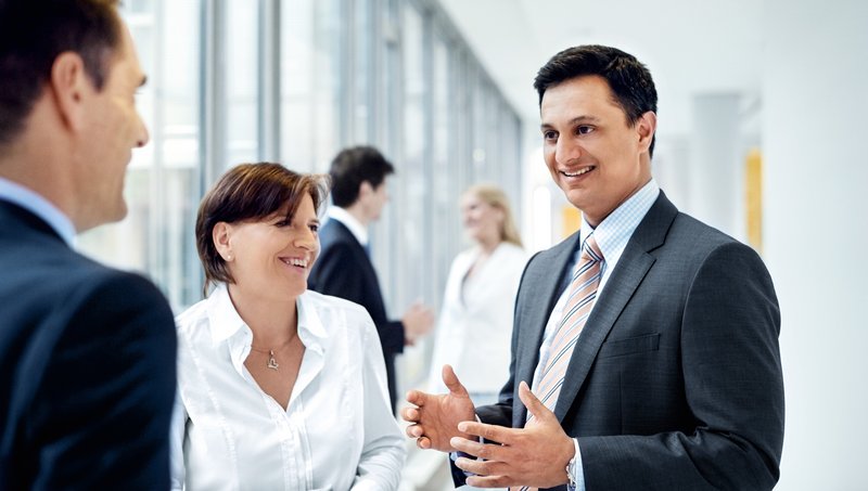 Patru colegi internaționali merg împreună pe hol