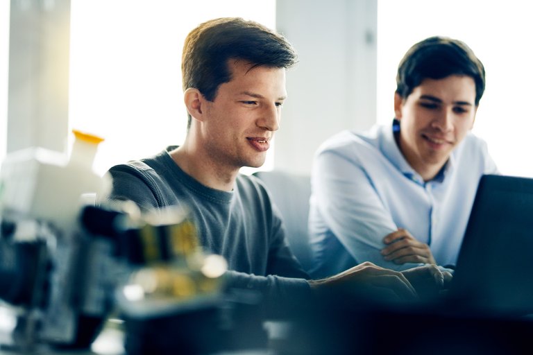 Zwei Männer schauen gemeinsam auf einen Laptop