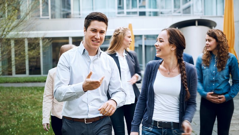 Eine Gruppe Menschen unterhalten sich bei einem Spaziergang durch eine Parkanlage