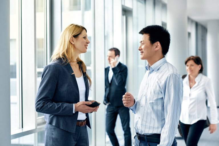 A woman and a man are talking to each other in a hallway